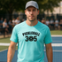 Man wearing a turquoise t-shirt with 'Pickleball 305' on a tennis court