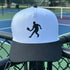 White and black cap with a tennis player silhouette on a tennis court background