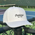 White cap with 'Pickleball Est. 1965' text on a tennis court background