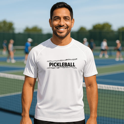 Man wearing a white 'Pickleball' t-shirt on a tennis court with other players in the background.